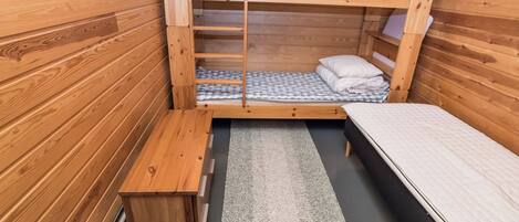 A compact wooden room with bunk beds, a small bench, and a rug.