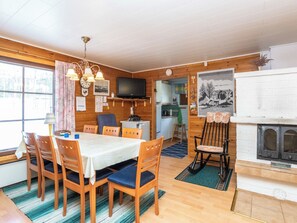 A cozy cabin interior with a dining area, kitchen, and a fireplace. - Mäntyrinne by Interhome (Kerimäki)