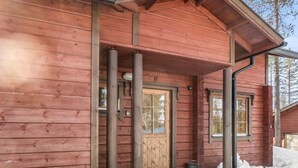 Une cabane en bois avec une porte en bois, un petit porche et une fenêtre.