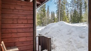 Une cabane en bois avec un porche, un banc en bois et un sol recouvert de neige.