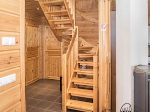 A wooden interior with a staircase leading to upper floors, a tiled floor, and a no-smoking sign.