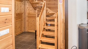 Un intérieur en bois avec un escalier en colimaçon, des murs en bois et un sol carrelé.