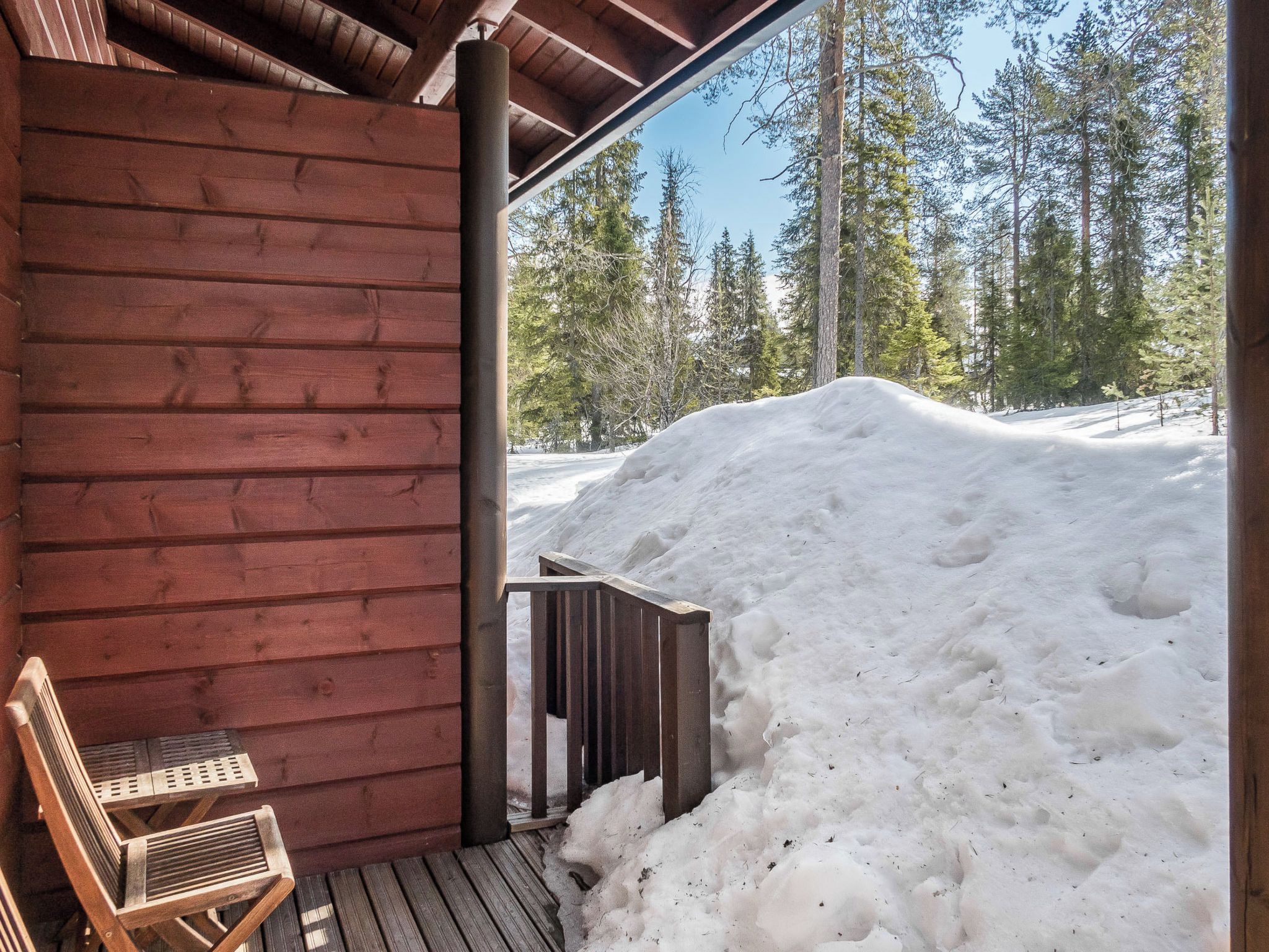 Une cabane en bois avec une véranda couverte et une chaise.