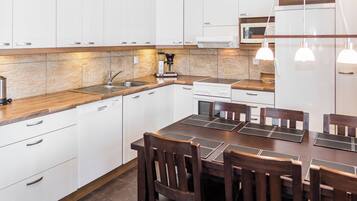 A modern kitchen with white cabinets, a wooden countertop, and a dining area with a table and chairs.