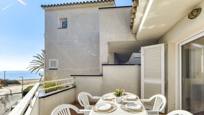Ein Balkon mit Tisch für vier Personen, weißen Plastikstühlen und Meerblick.