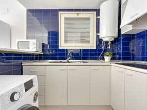 Een koelkast, een microgolfoven, kookgerei, borden en bestek