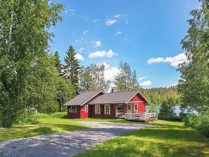 A red cabin with a gravel driveway leading to a dock, surrounded by lush greenery and a lake. - Pajaranta by Interhome (Hartola)