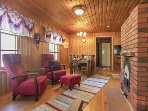 A cozy cabin interior with wooden walls, a dining area, and a fireplace. - Pajaranta by Interhome (Hartola)