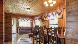 A cozy cabin interior with wooden walls, a dining area with wooden chairs, a sofa, and a rug. - Pajaranta by Interhome (Hartola)