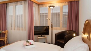 Een hotelkamer met een bed, een televisie, een bureau, een stoel en een lamp.