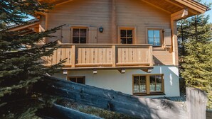 Une maison en bois à deux étages, dotée d’un balcon, de grandes fenêtres et d’un toit en pente.