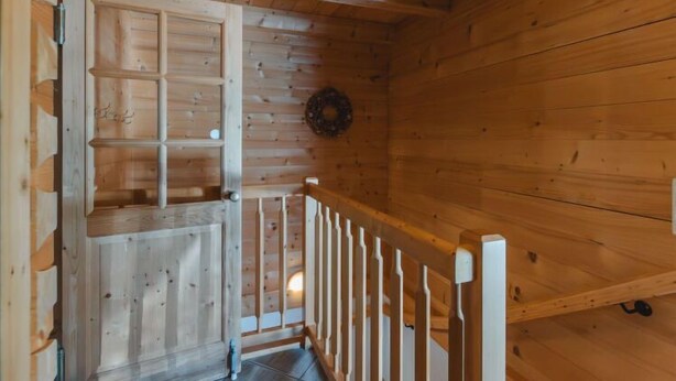 Un intérieur en bois avec un escalier, des murs en bois et une porte dotée d’une étagère.