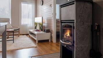 Una sala de estar acogedora con chimenea, una zona de estar cómoda y un televisor.