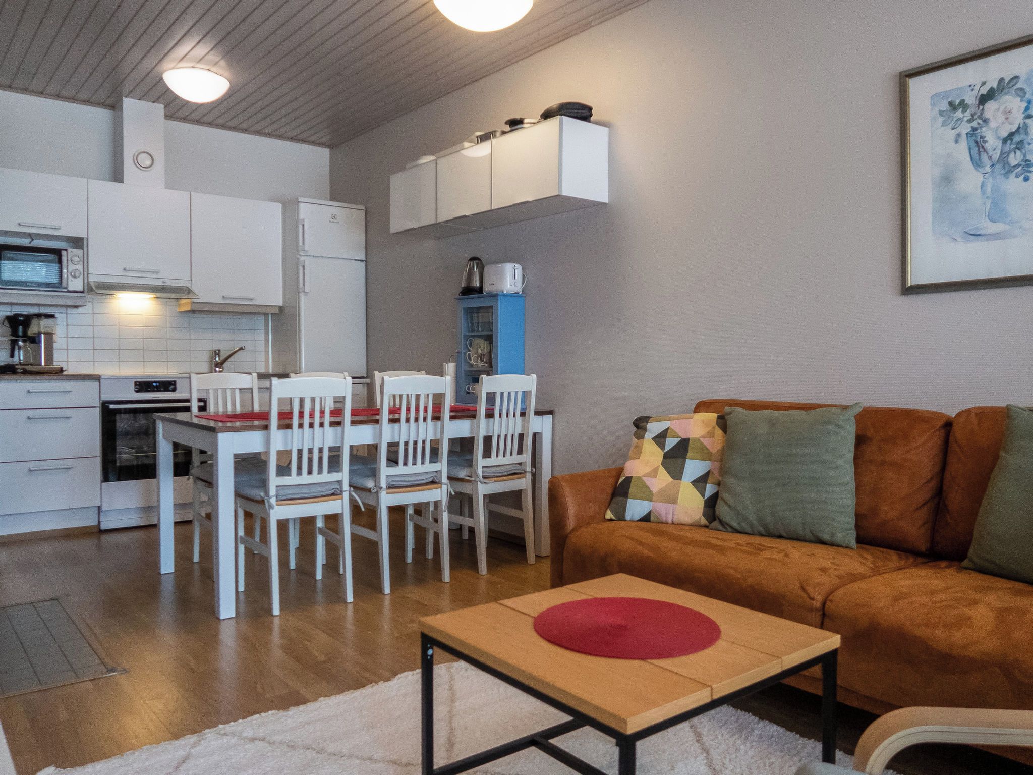 A compact living space with a kitchenette, dining area, and a sofa with cushions.