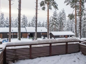 A snow-covered landscape with a wooden fence, a building with a snow-covered roof, and tall pine trees. - Vacation home Kerttu by Interhome (Sotkamo)