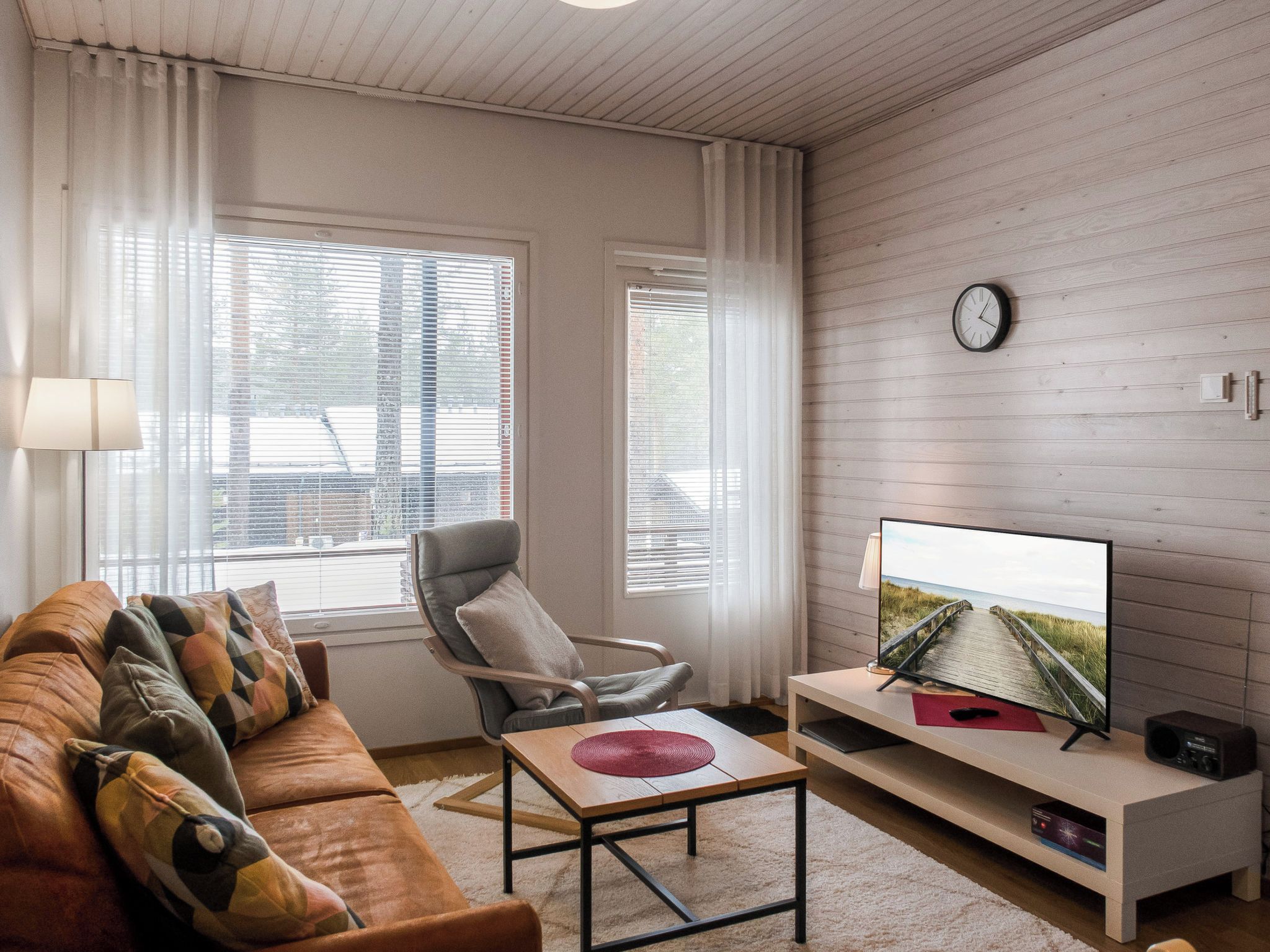 Una sala de estar con sofá, sillón, televisión y una pared de madera.
