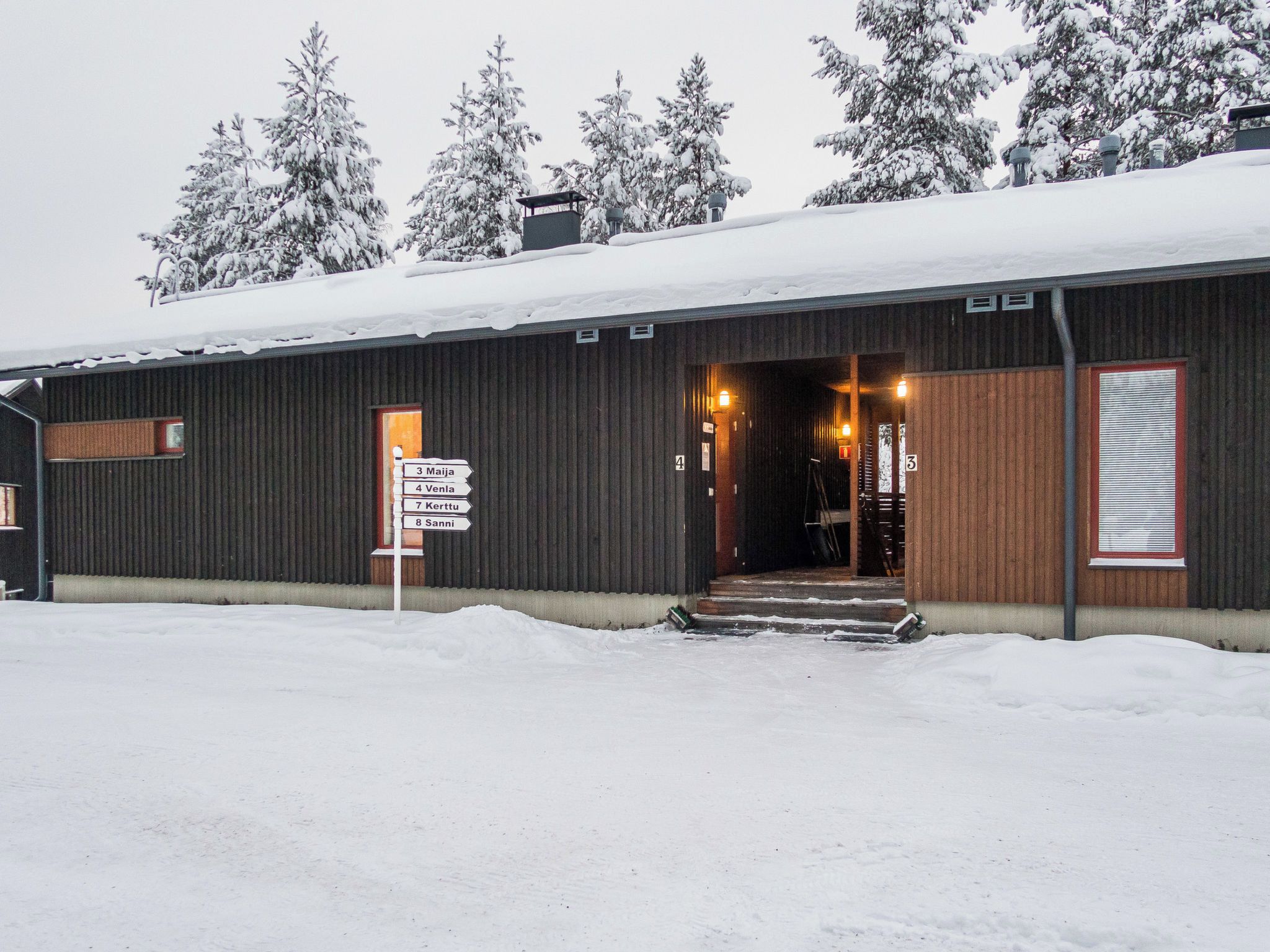 A building with a metal exterior, a wooden door, and a signpost with directions.