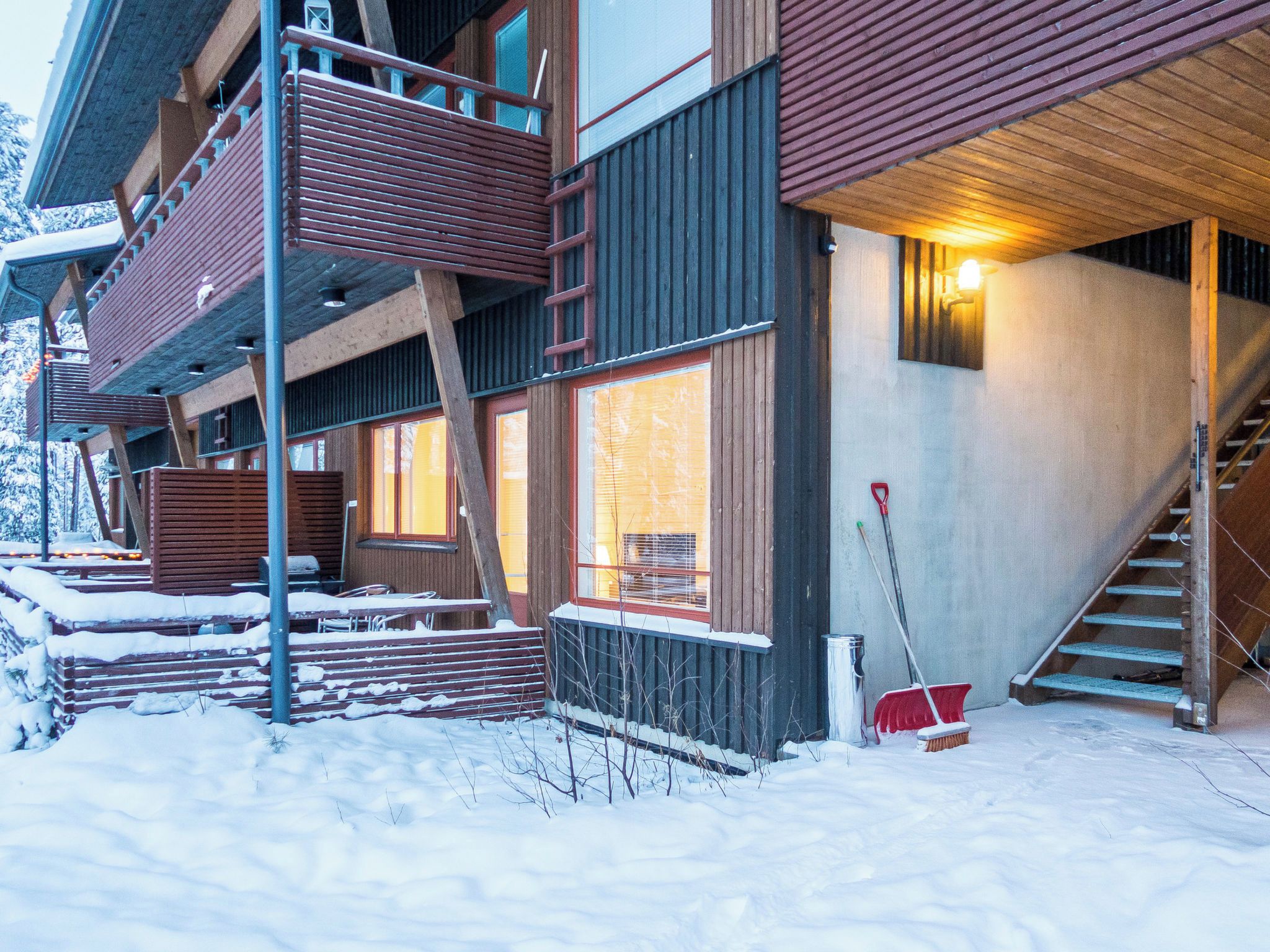 Un immeuble à plusieurs étages doté d’un balcon en bois, de grandes fenêtres et d’un escalier menant à un niveau supérieur.