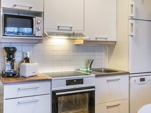 A modern kitchen with white cabinetry, a built-in microwave, a toaster, and a stove. - Vacation home Kerttu by Interhome (Sotkamo)