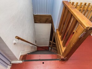 A staircase with a wooden handrail and a red carpeted landing.