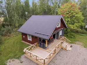 Une cabane dotée d’une terrasse en bois et d’un porche abrité.