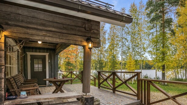 A wooden cabin with a porch, a table with chairs, and a lantern.