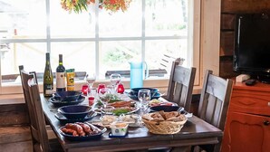 A dining table set with various dishes, wine bottles, and glasses, positioned in front of a large window with a view of greenery outside.