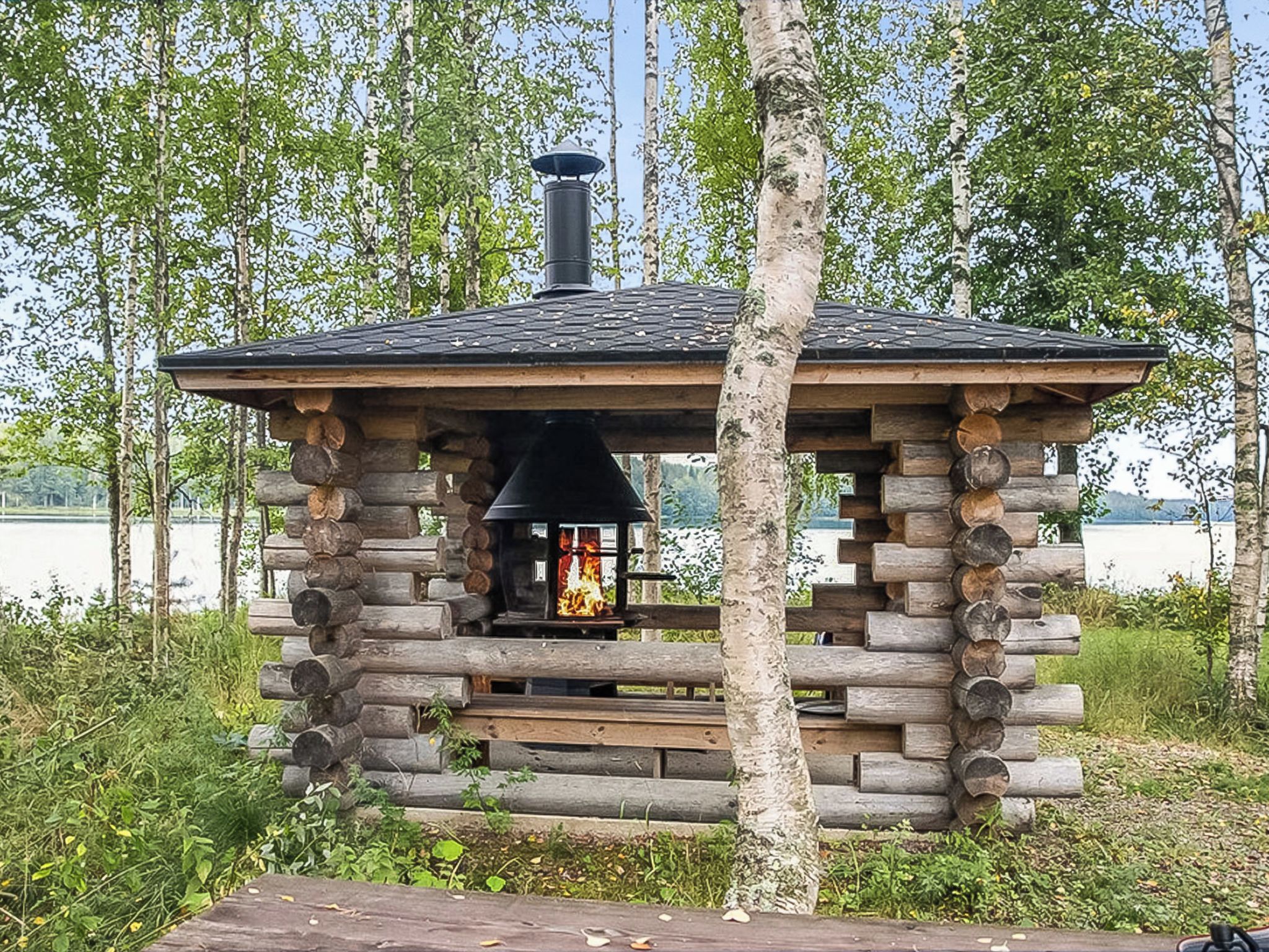 Hirsihökkelissä on savupiippu, nuotiopaikka ja penkki.