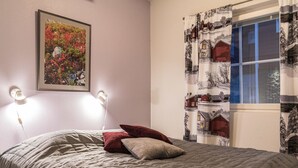 Een slaapkamer met een bed, een ingelijste foto aan de muur en een raam met gordijnen.