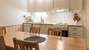Een moderne keuken met witte kastjes, een houten eettafel en een gasfornuis.