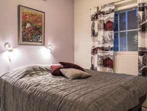 Ein Schlafzimmer mit einem Bett, einem gerahmten Bild an der Wand und einem Fenster mit Vorhängen.
