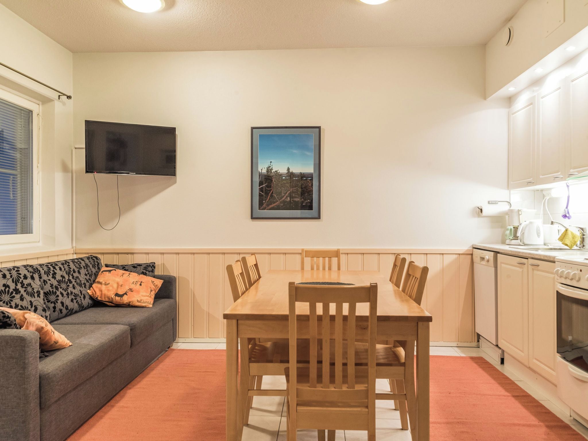 Ett kompakt bostadsutrymme med en soffa, ett matbord och ett köksområde.