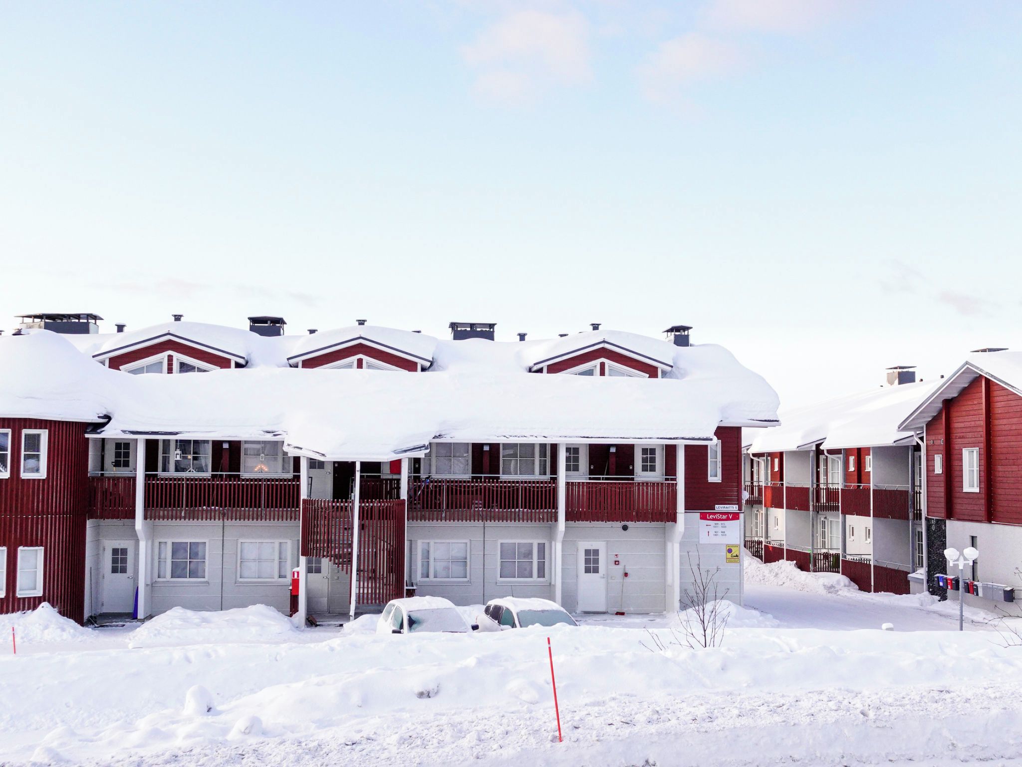 En rad röda byggnader med snötäckta tak och en klar himmel.