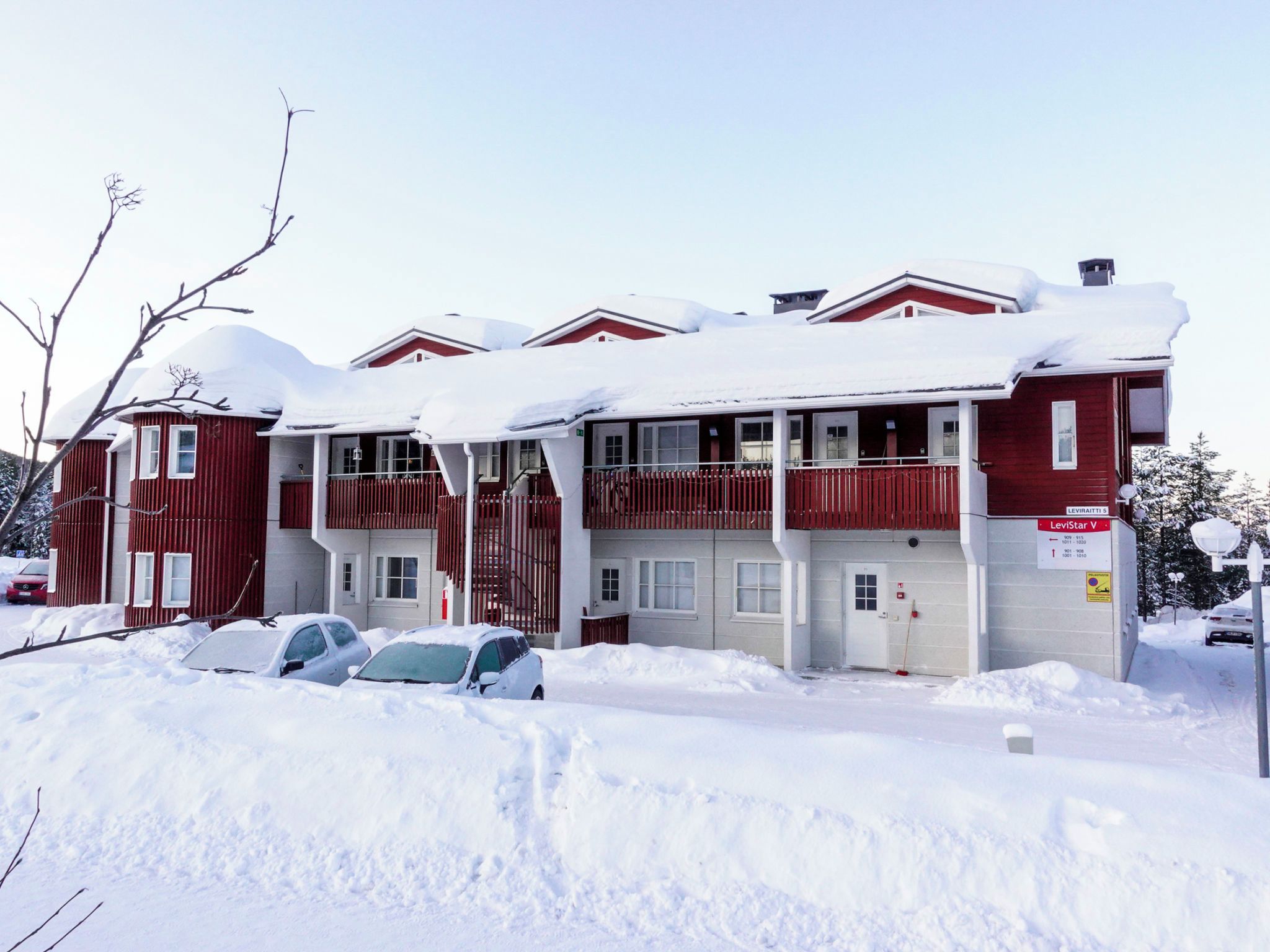 A red building with multiple windows and balconies, surrounded by snow.