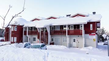 A red building with multiple windows and balconies, surrounded by snow.