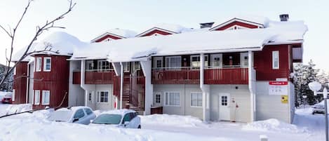 Ein rotes Gebäude mit mehreren Fenstern und Balkonen, umgeben von Schnee.