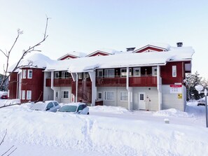 A red building with multiple windows and balconies, surrounded by snow.