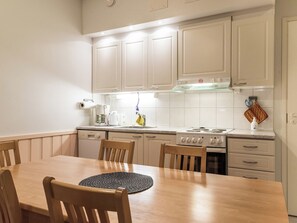 A kitchen with white cabinets, a stove, a sink, and a dining table with chairs.