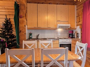 Cocina de cabaña de madera con una mesa y sillas, estufa y cafetera.