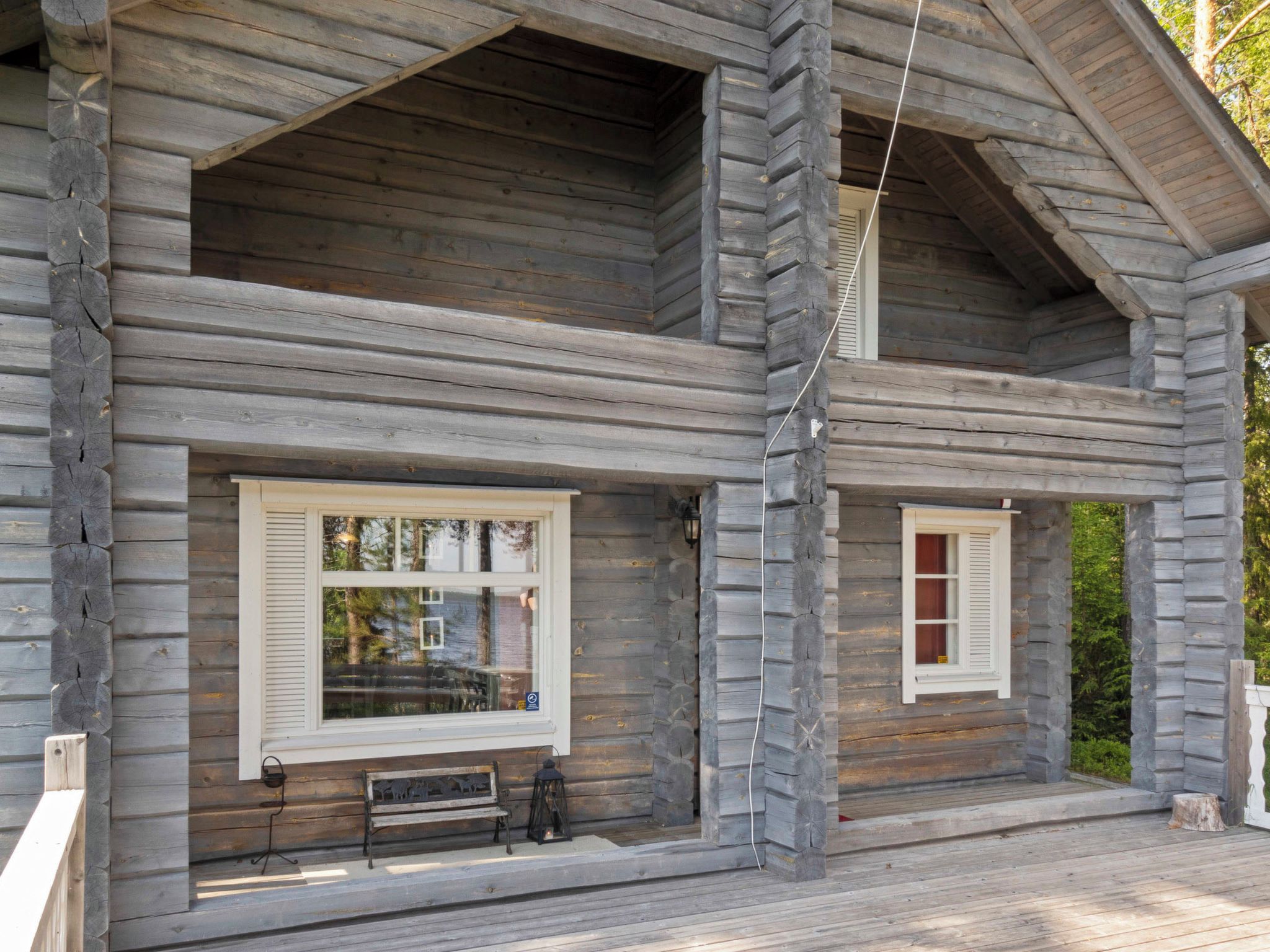A log cabin with a porch, two windows with shutters, and a bench.