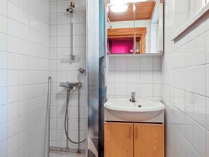 Un baño con ducha, lavamanos y espejo.