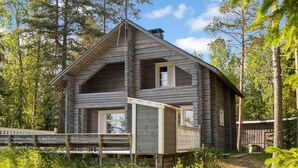 A rustic cabin with a gabled roof, a front porch, and a small deck.