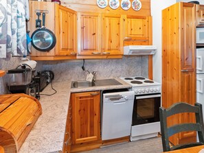 Una cocina compacta con muebles de madera, estufa, lavavajillas y pileta.
