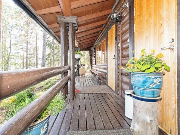 Una cabaña de madera con un porche cubierto, una banca y una planta en maceta.