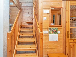 A wooden staircase leading to a room with a calendar, a coat rack, and a door with a window. - Kinostupa 1a (2) by Interhome (Kuusamo)