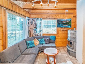 A cozy cabin interior with a gray sectional sofa, a small round table, and a fireplace.