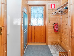 A narrow hallway with a wooden door, a fire extinguisher, and a number sign.