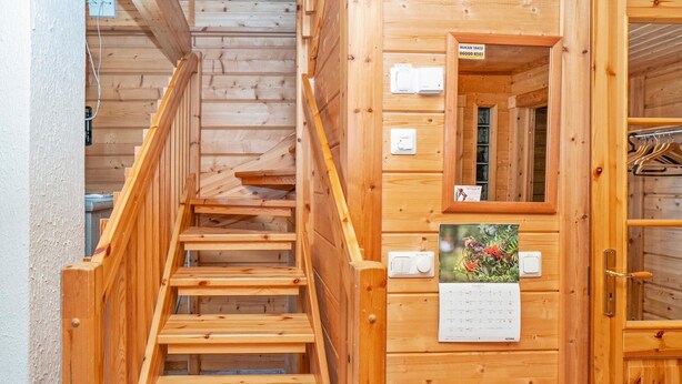 Una escalera de madera que lleva a una habitación con un calendario y una puerta con manija.