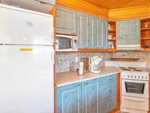 A kitchen with a refrigerator, microwave, coffee maker, and stove. - Kinostupa 1a (2) by Interhome (Kuusamo)