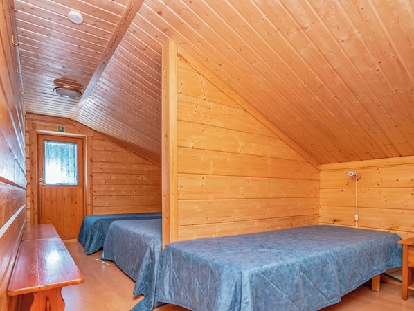 A cabin with two beds, a bench, and a window.